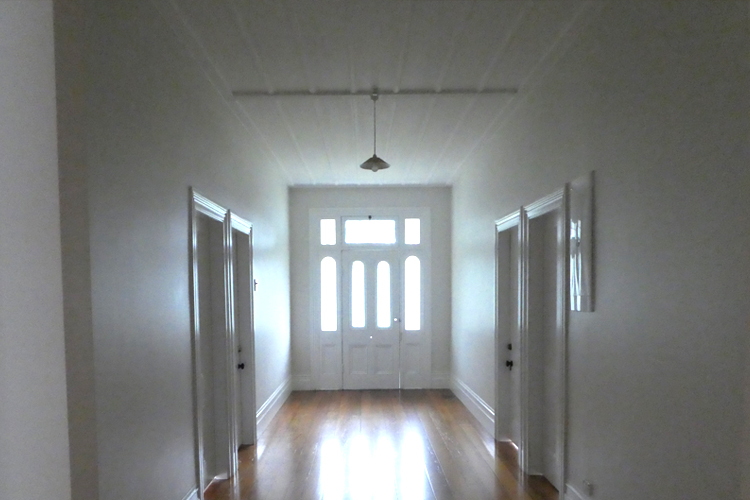 Polished floors with white front door and white walls with a battened ceiling