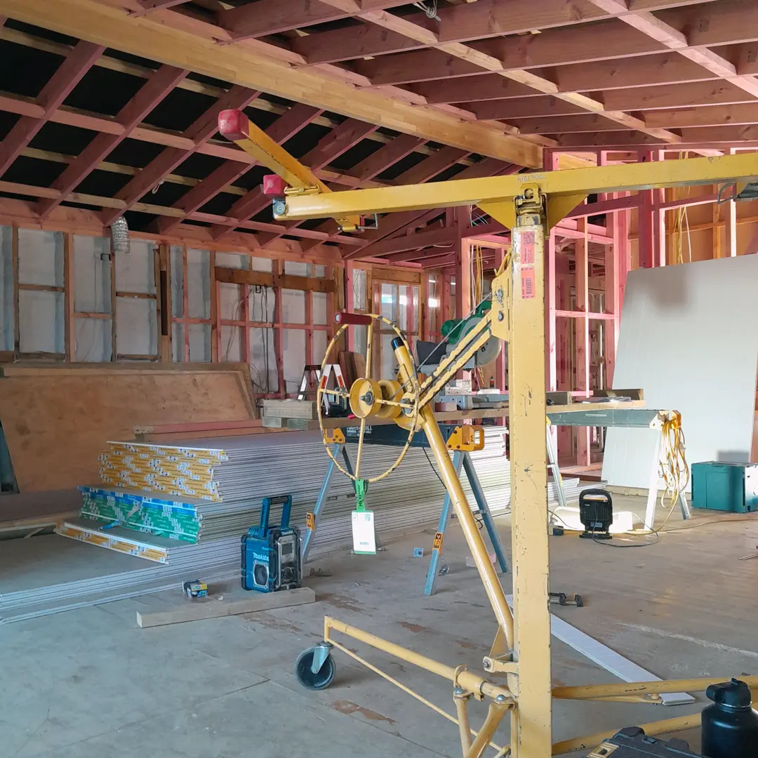A construction crane in action, raising a substantial piece of wood with precision.
