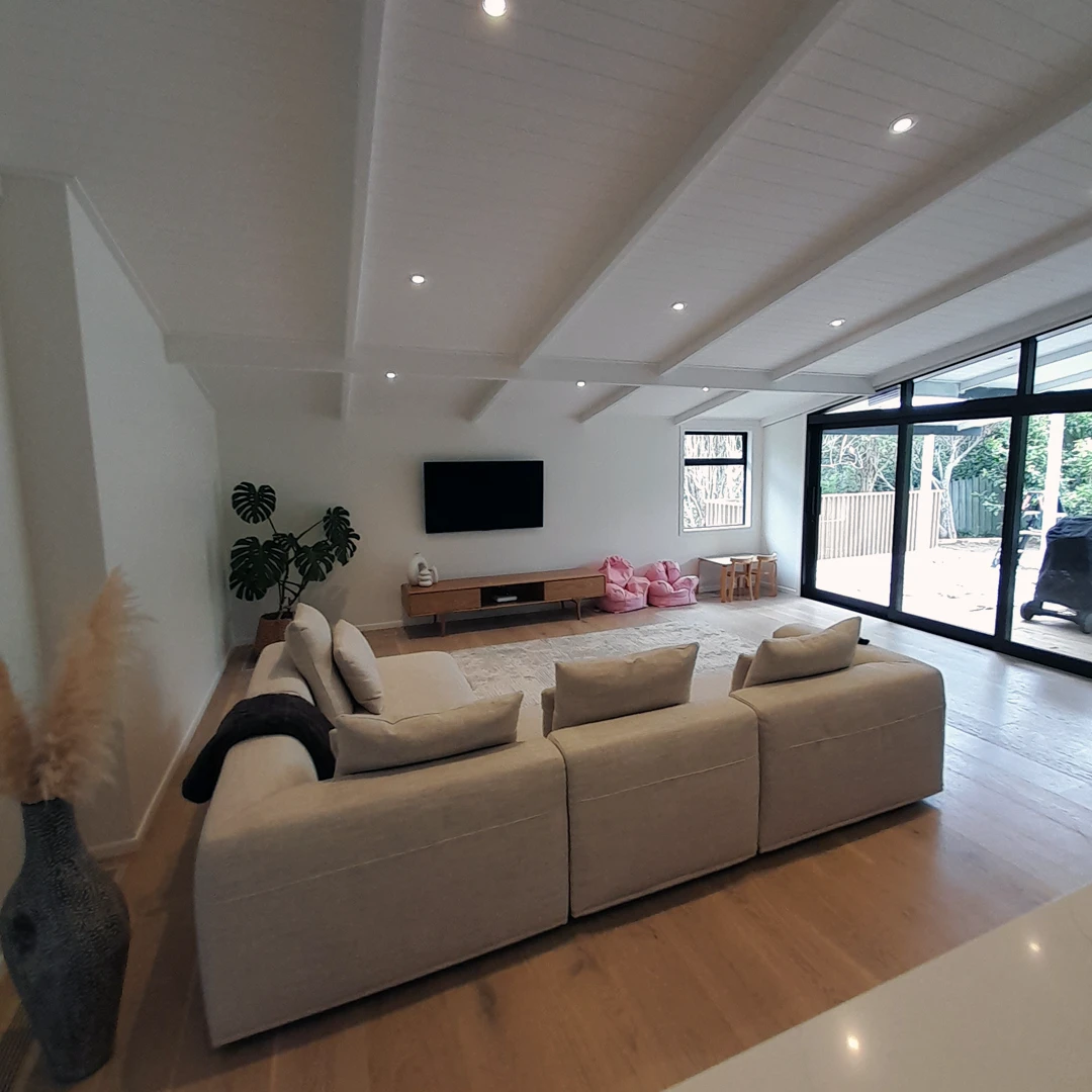 A cozy lounge with a couch, TV, and chair in a well-furnished living room.
